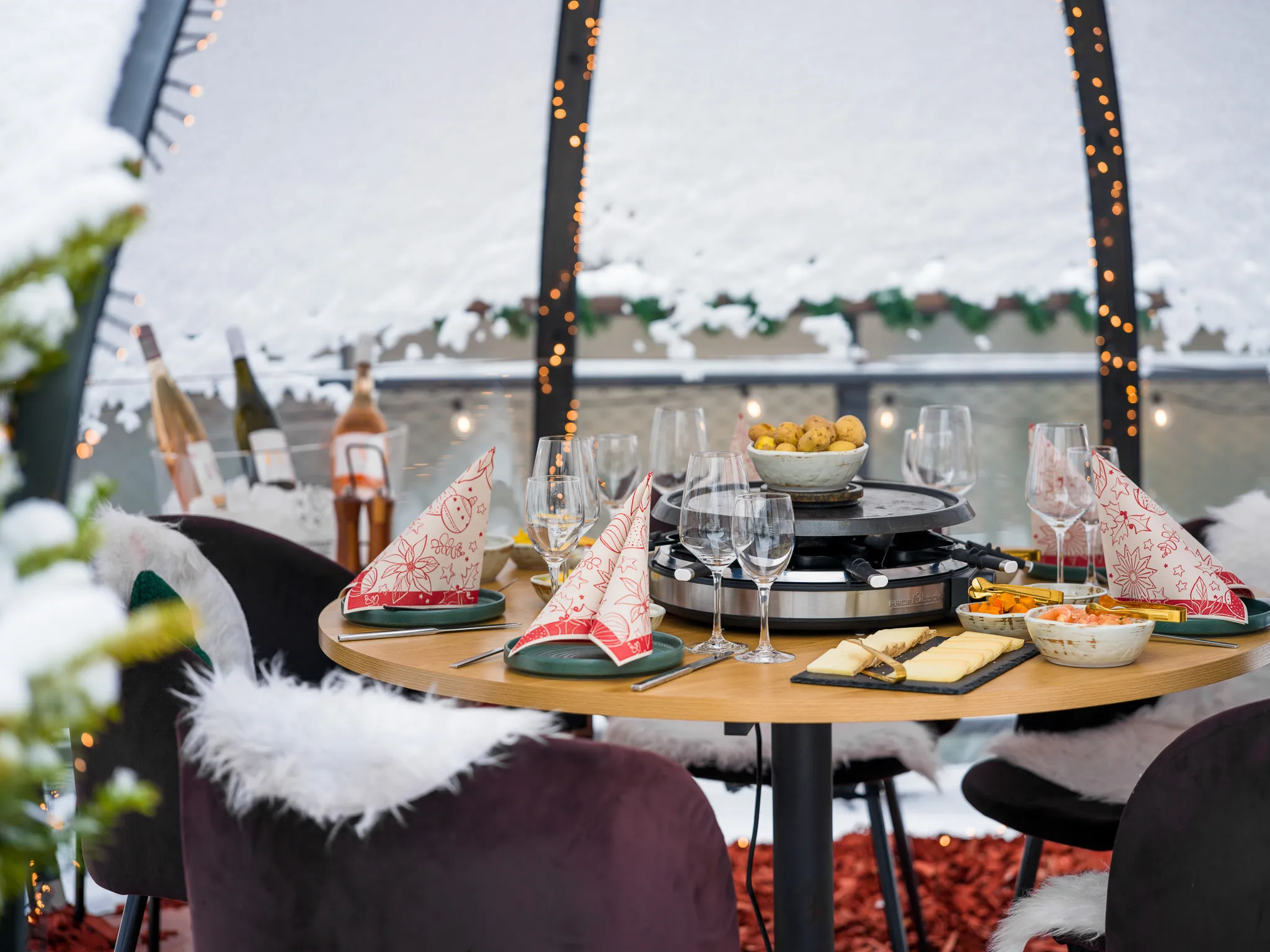 Gedeckter Raclette-Tisch im verschneiten Iglu mit Blick auf den Neckar