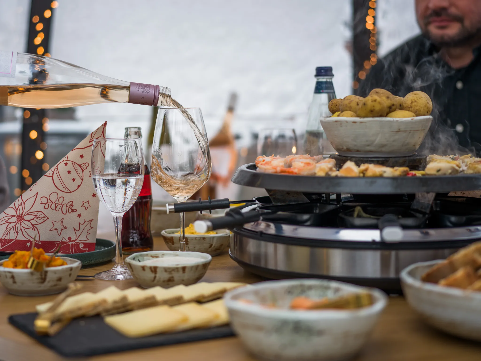 Wein wird am Raclette-Tisch im Iglu eingeschenkt